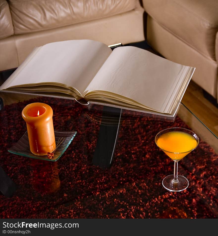 An empty photo album on a glass table with a candle in a romantic setup. An empty photo album on a glass table with a candle in a romantic setup