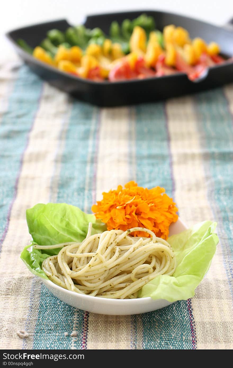 Pasta olio with lettuce and edible flower and colorful rows of capsicums. Pasta olio with lettuce and edible flower and colorful rows of capsicums