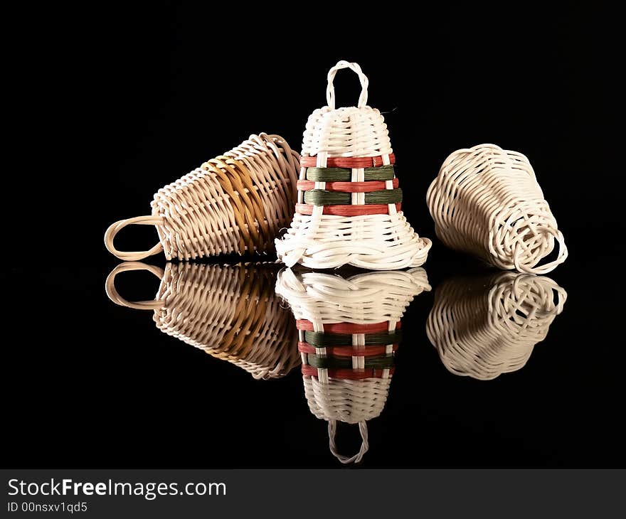 Wicker Christmas bells on a reflective black background. Wicker Christmas bells on a reflective black background