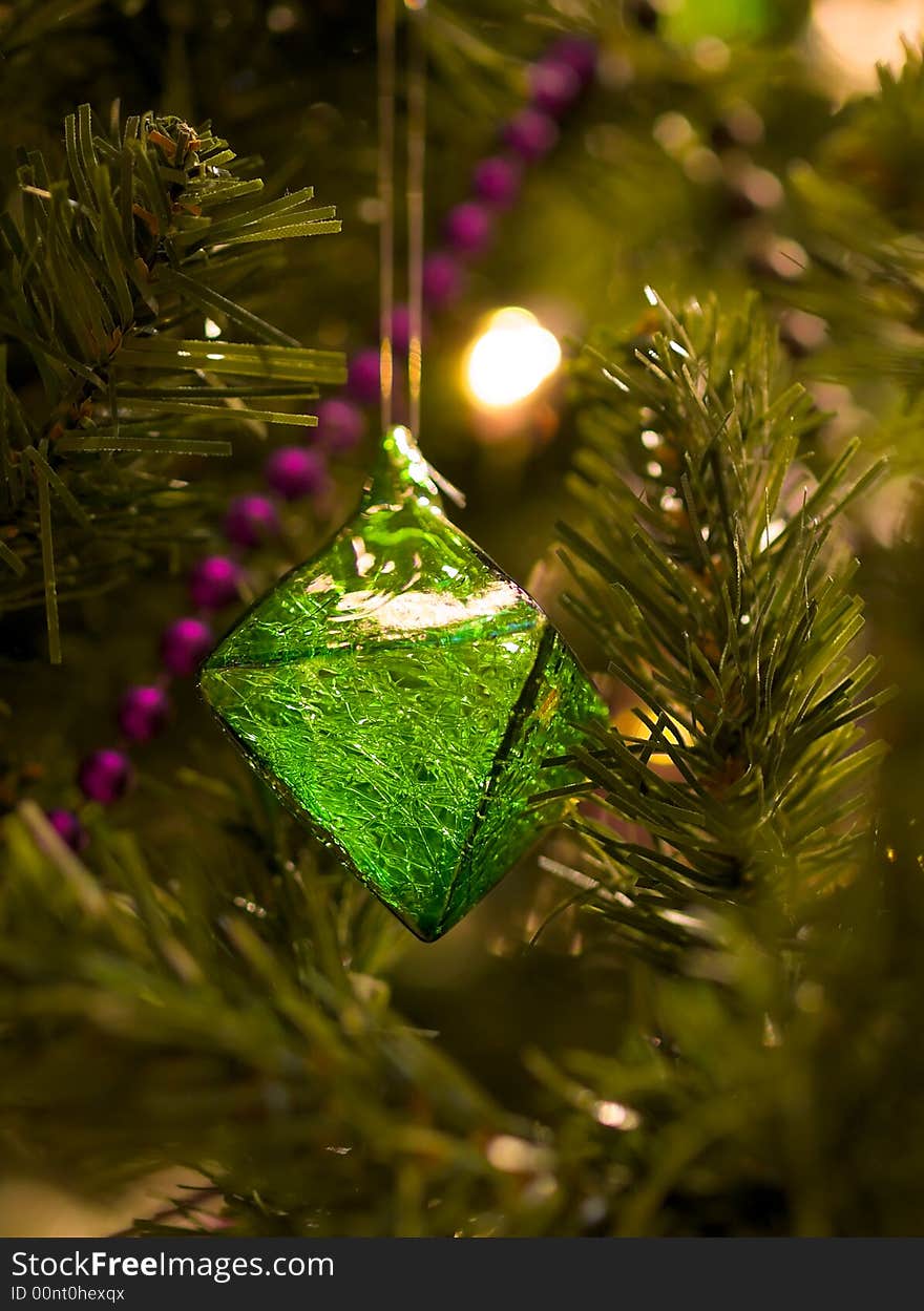 A double tetrahedral green ornament full of fractured textures withing its translucent body hanging on a Christmas tree