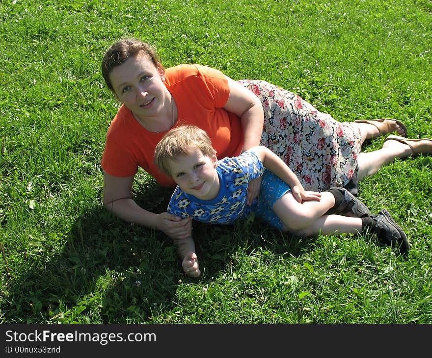 Mother and her small son sitting on green grass. Mother and her small son sitting on green grass