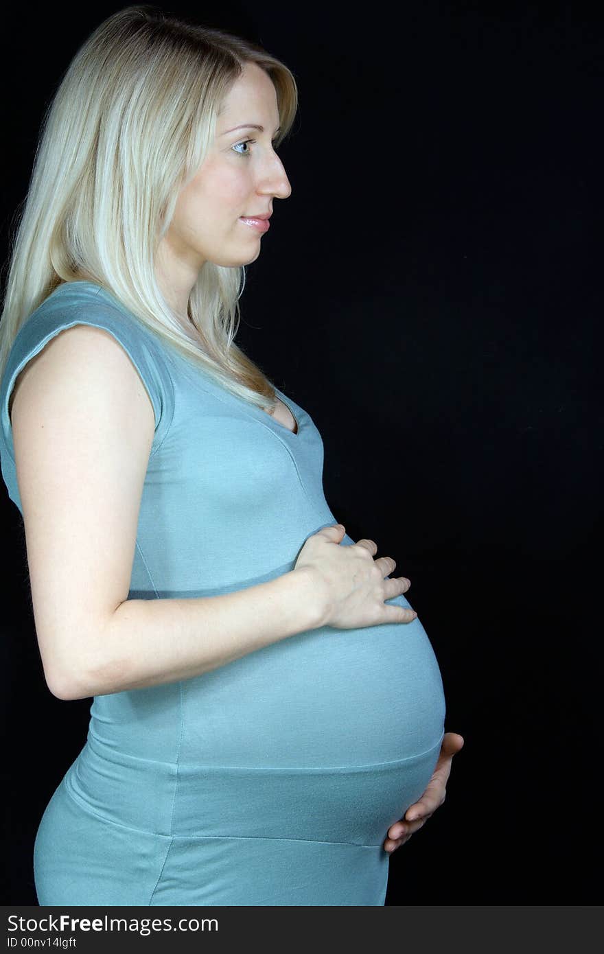 Happy pregnant woman standing on black