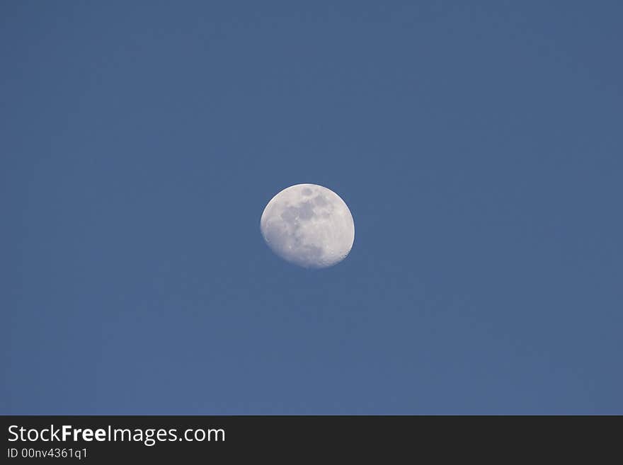 The Moon centered in a medium blue sky