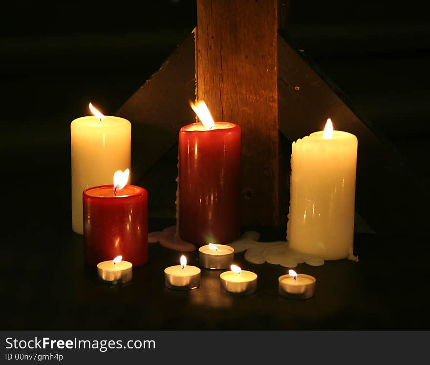 Candles set against a rough wood beam in the darkness. Candles set against a rough wood beam in the darkness