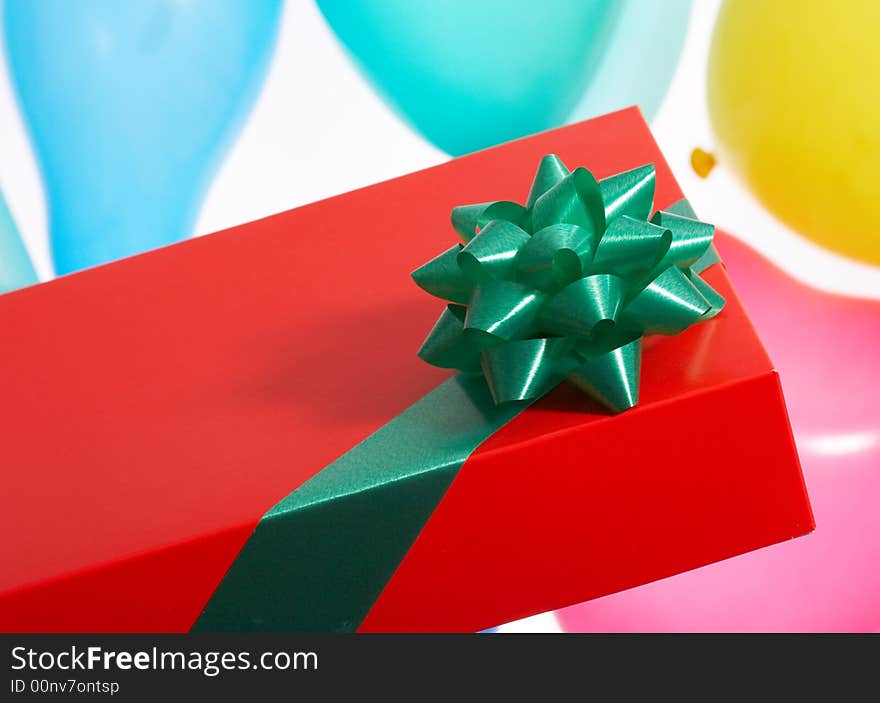 A red giftbox with green ribbon over the balloon background. A red giftbox with green ribbon over the balloon background