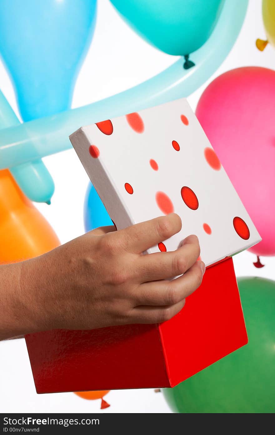 A hand holds a red gift box over the balloons. A hand holds a red gift box over the balloons