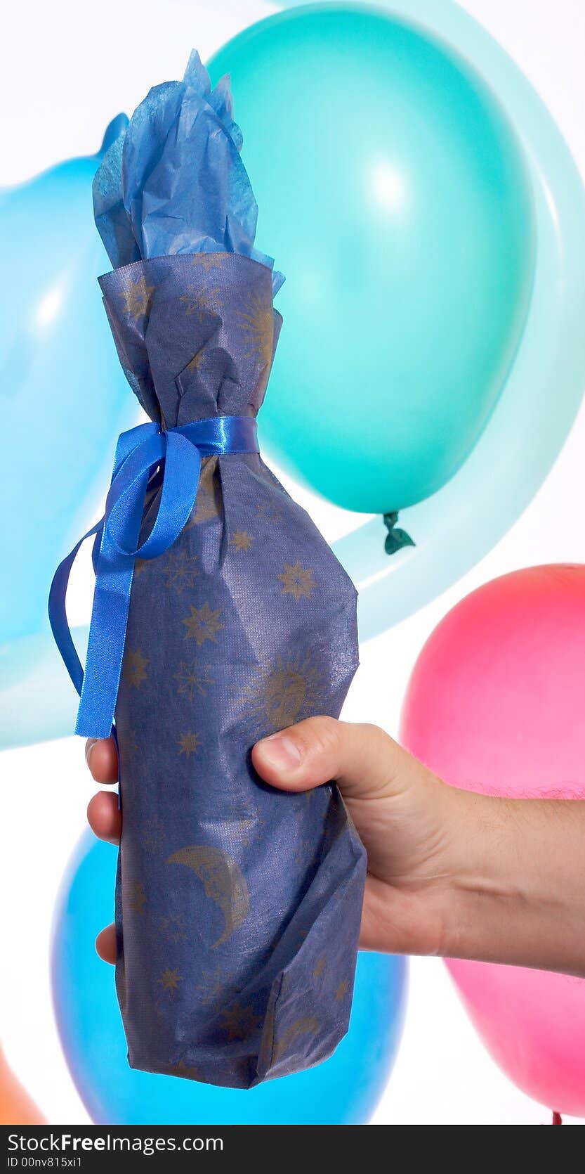 A hand holding wrap bottle over the balloons. A hand holding wrap bottle over the balloons