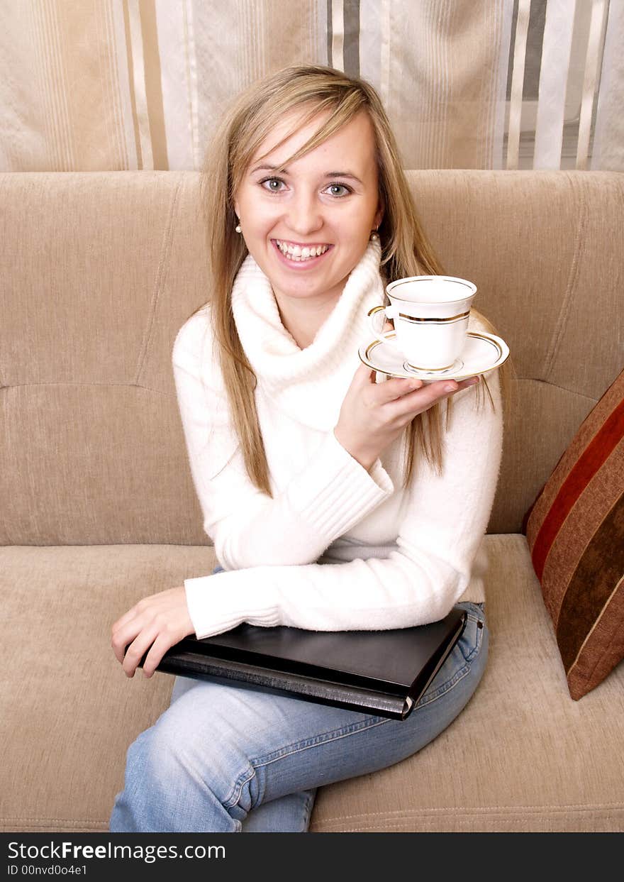 Beautiful female student after lecture on the couch with coffee and folder. Beautiful female student after lecture on the couch with coffee and folder.