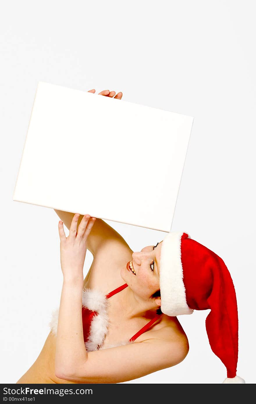 Beautiful girl in christmas bikini and with christmas hat is holding up a white sign for copy space. With background clipping path for your convenience. Beautiful girl in christmas bikini and with christmas hat is holding up a white sign for copy space. With background clipping path for your convenience