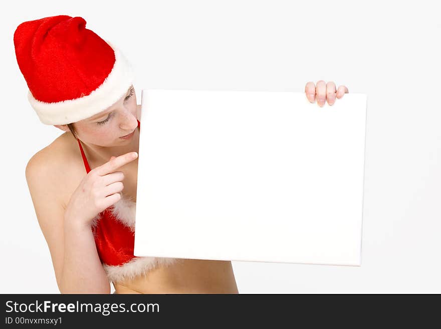 Beautiful girl in christmas bikini and with christmas hat is holding up a white sign for copy space. With background clipping path for your convenience. Beautiful girl in christmas bikini and with christmas hat is holding up a white sign for copy space. With background clipping path for your convenience