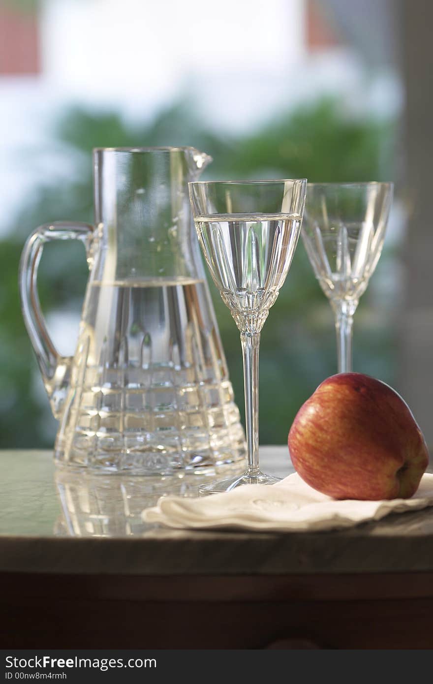 Carafe of water with glasses and apple