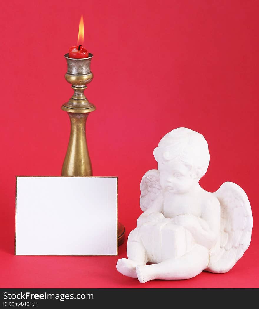 Christmas candle with flame.A white card in front.Red background. Christmas candle with flame.A white card in front.Red background.