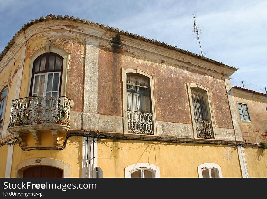 Rustic apartment building in Portimao, Portugal showing sun damaged stucco and rusted wrought iron balconies