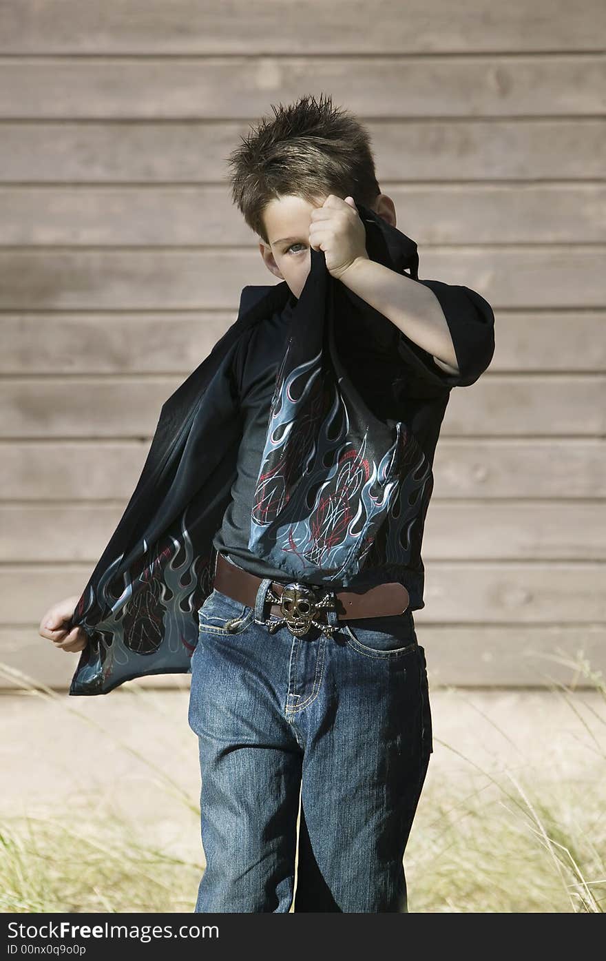 Little boy hides his face behind the tail of his own shirt. Little boy hides his face behind the tail of his own shirt.