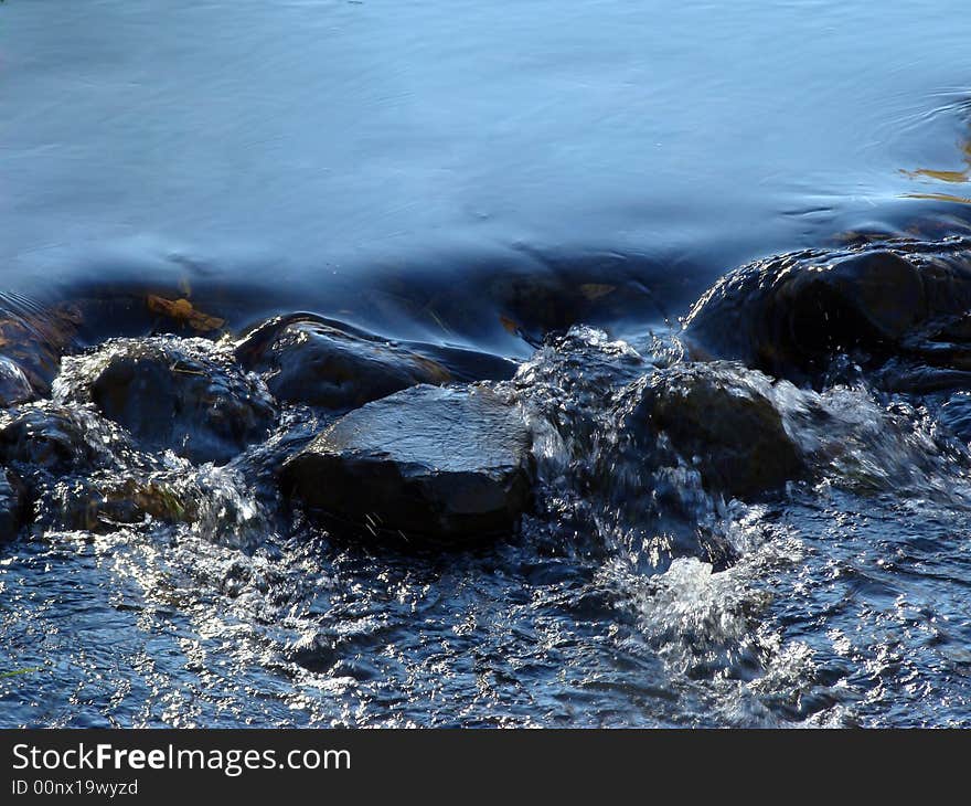 Blue water in a creek flowing over rocks. Blue water in a creek flowing over rocks.