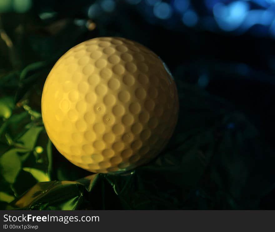 Close up of golf ball on crumpled foil with yellow lighting effect. Close up of golf ball on crumpled foil with yellow lighting effect