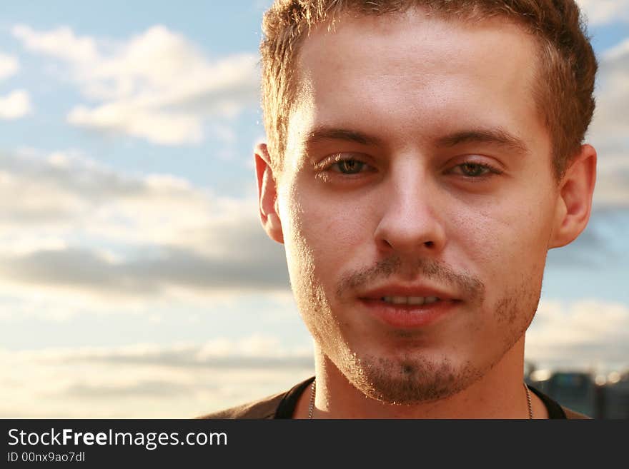 Young man against blue cloudy sky