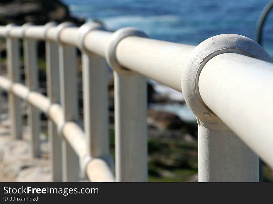 Looking along a curved white handrail by the ocean. Looking along a curved white handrail by the ocean