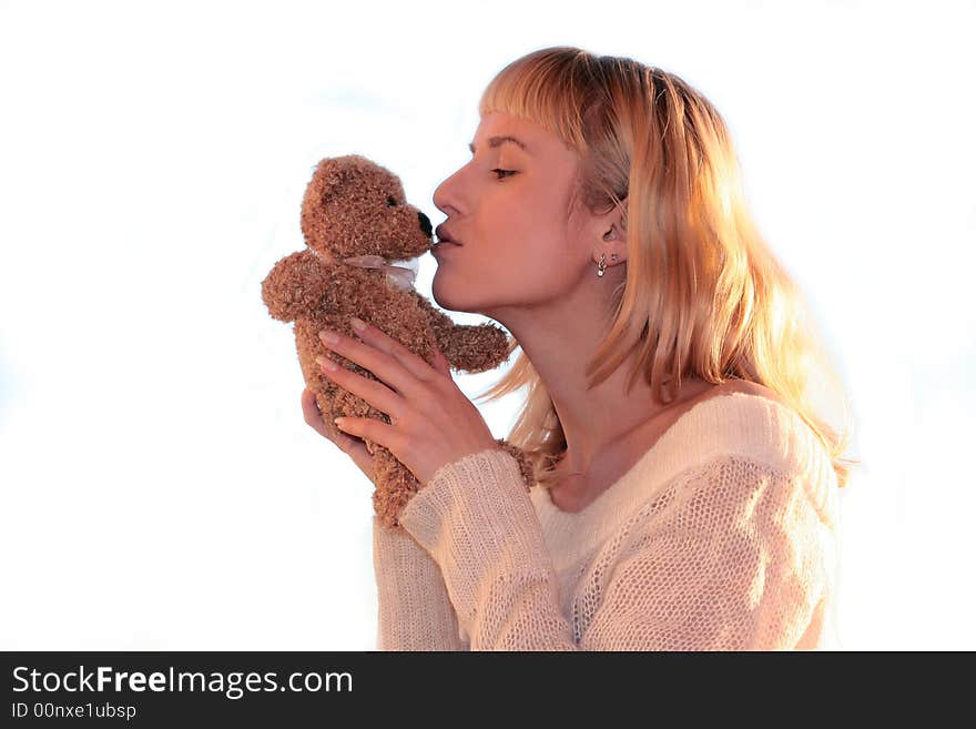 Young blond woman is kissing teddy bear