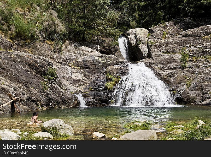 Girl in a lake with a waterfall