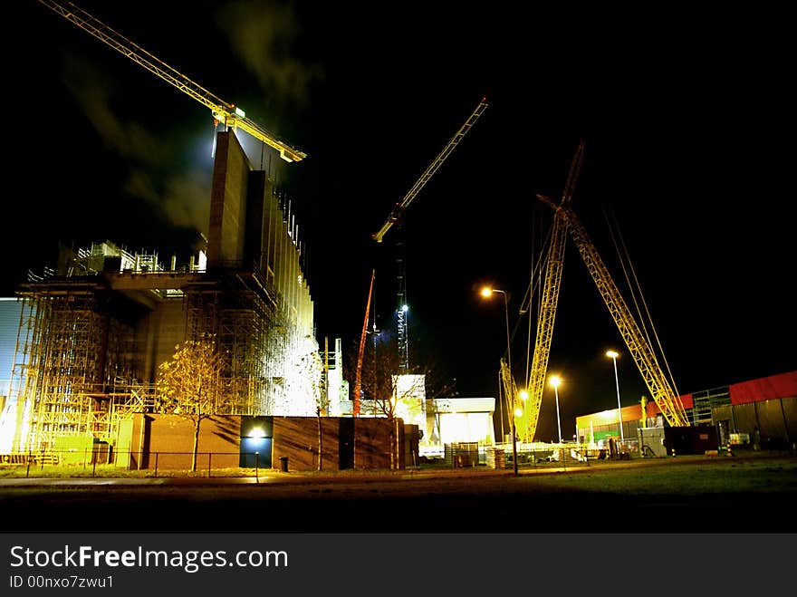 Buildingsite with cranes at night. Lights are kept on for workers at night.