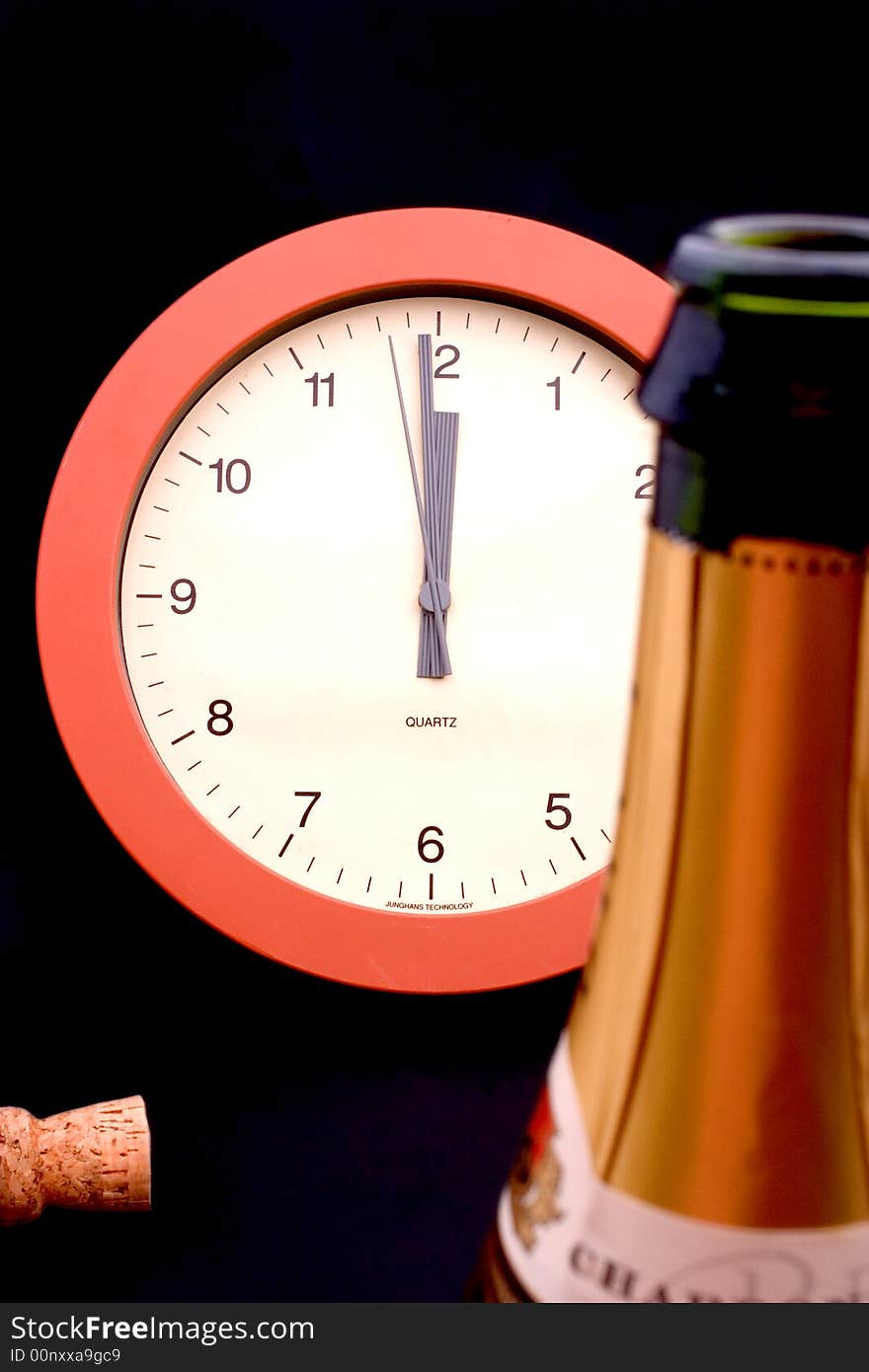 A clock ticking away the final seconds behind an uncorked bottle of champagne, shallow DOF, focus is on the clock