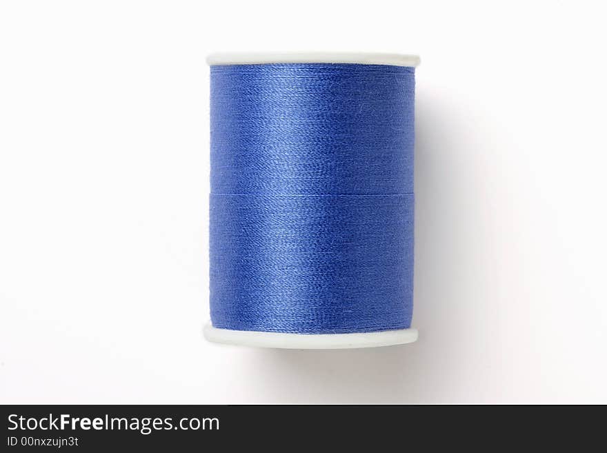 Spindle of blue thread isolated on white background