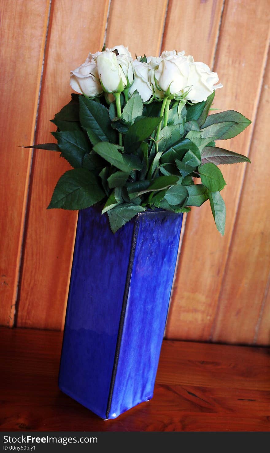 White long stemmed roses in a blue vase.