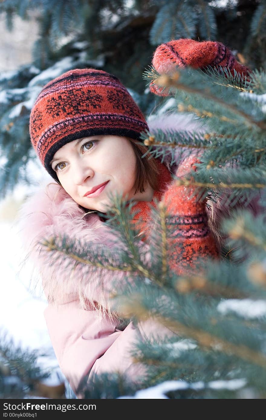 Beautiful girl in hat and mittens in snow-covered evergreens. Beautiful girl in hat and mittens in snow-covered evergreens