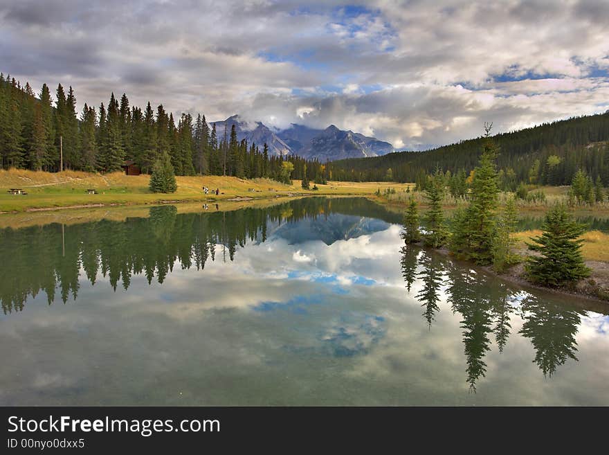 Lake in mountains surrounded by a wood and the cloudy sky above it. Lake in mountains surrounded by a wood and the cloudy sky above it