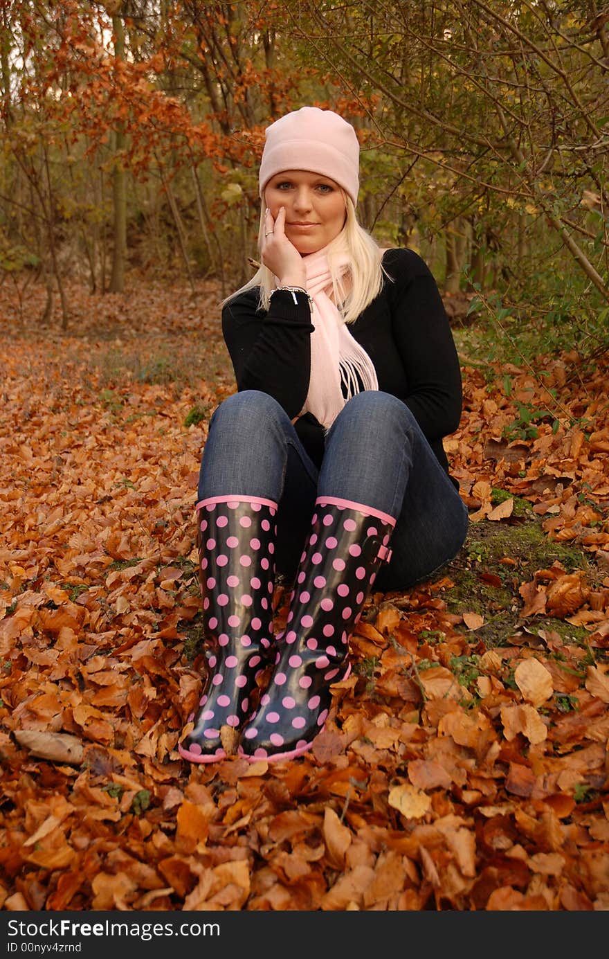 Attractive blonde sitting amongst fallen leaves in autumn. Attractive blonde sitting amongst fallen leaves in autumn.