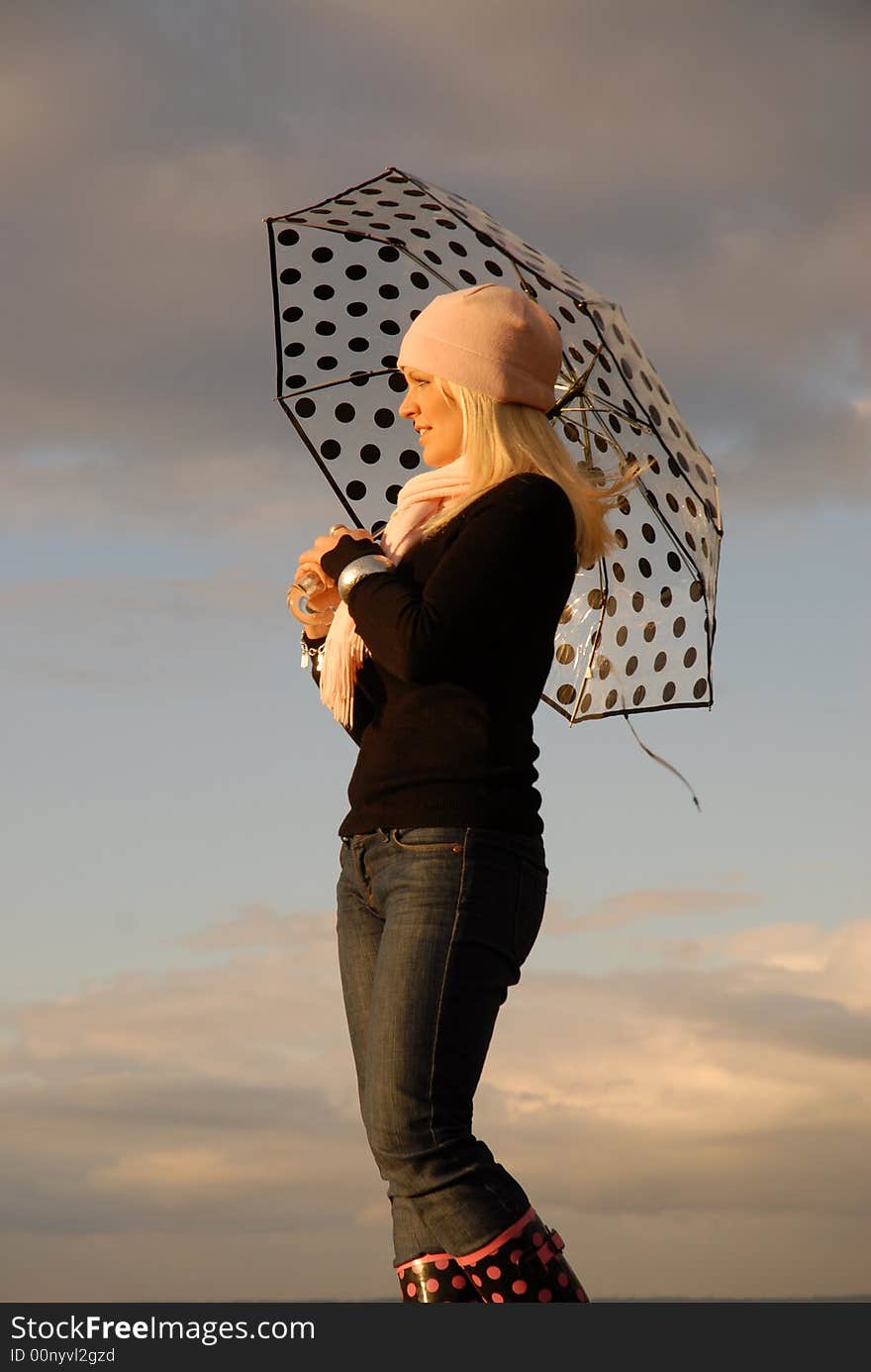 Attractive blonde holding umbrella background of cloudscape. Attractive blonde holding umbrella background of cloudscape.