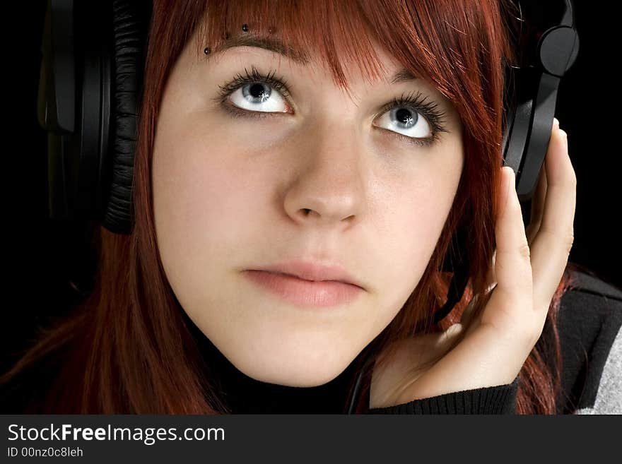 Pensive redhead girl listening to music and enjoying it (looking up, thinking).

Studio shot.