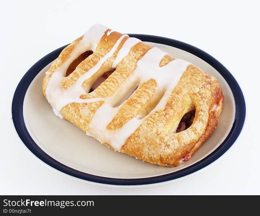 A cherry pastry on a plate against a white background. A cherry pastry on a plate against a white background.