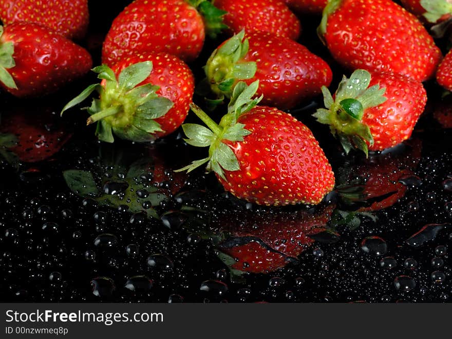 Fresh strawberries with water drops on wet black surface