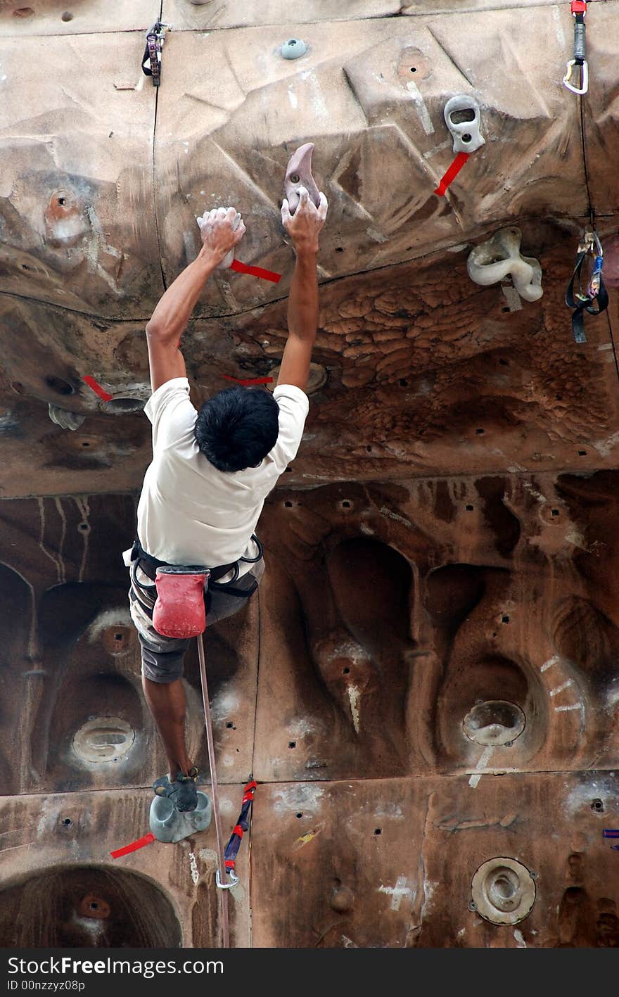 A young mountain climber scaling a wall. A young mountain climber scaling a wall