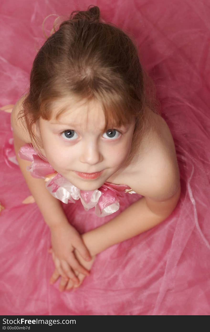 A girl in a pink dress looking up into a camera. A girl in a pink dress looking up into a camera