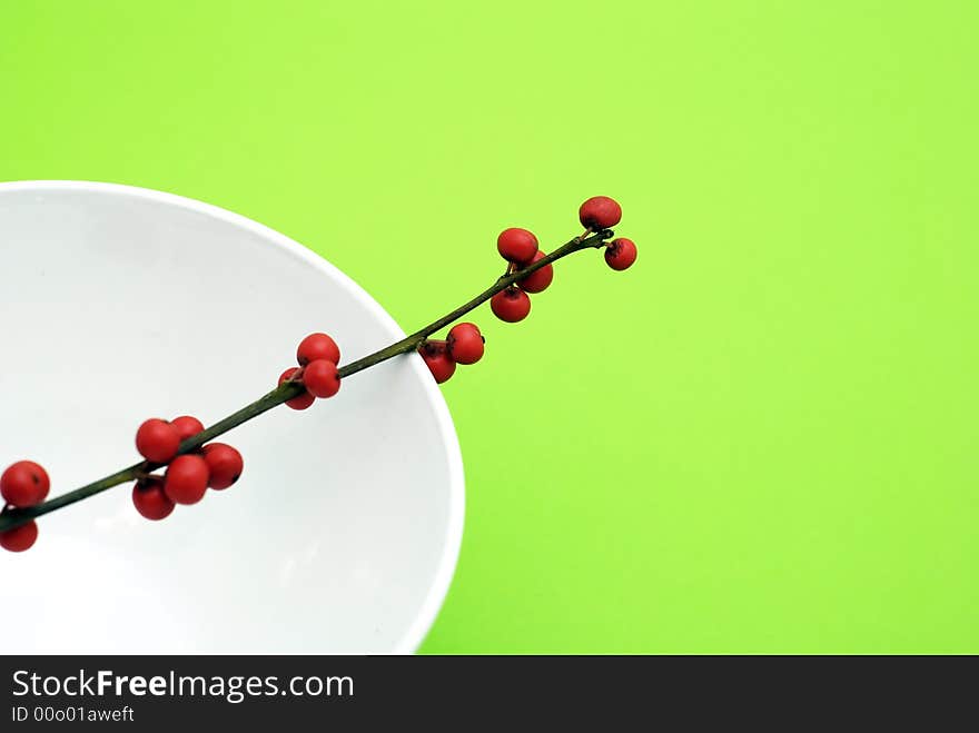 Bunch of red fruit of berry in the bowl on green background. Bunch of red fruit of berry in the bowl on green background