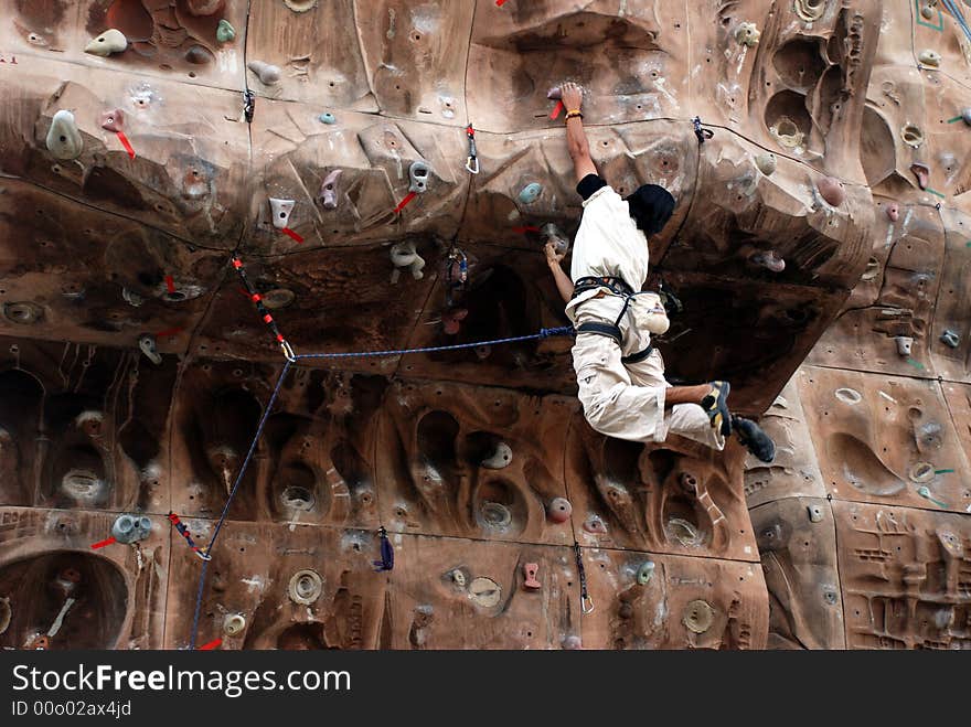 A young mountain climber scaling a wall. A young mountain climber scaling a wall