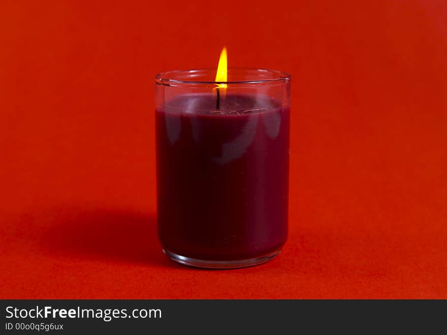 A small Christmas candle shot against a red background.