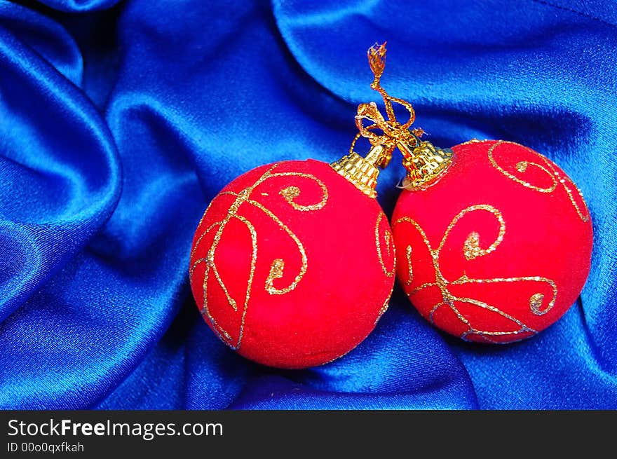 Two red Christmas balls on blue satin. Two red Christmas balls on blue satin