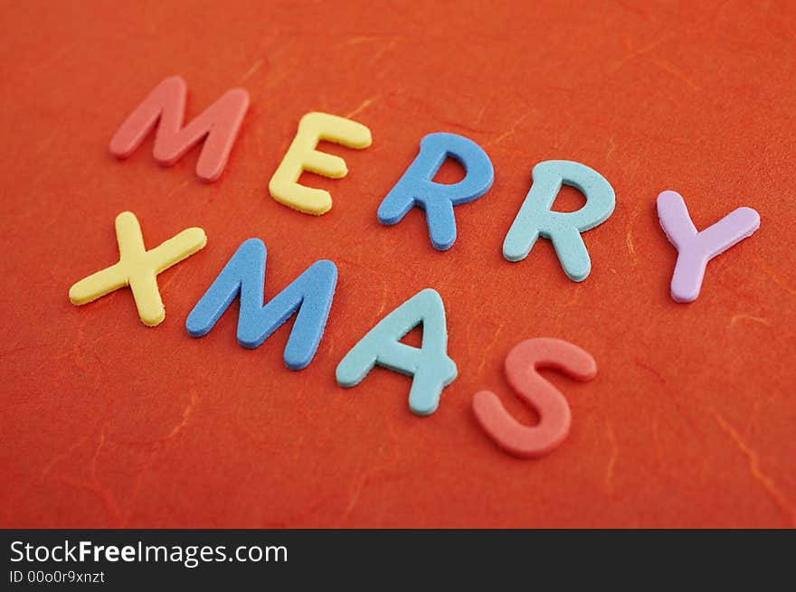 Merry christmas text (colorful soft rubber letters) on red silk paper