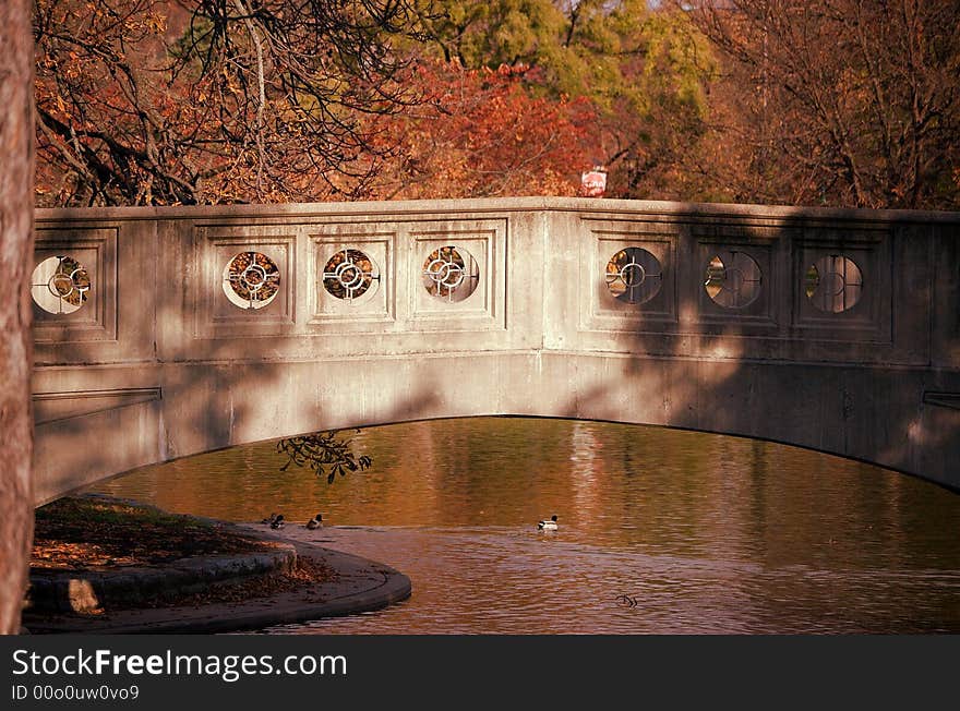 Gray stone bridge across golden autumn pond. Gray stone bridge across golden autumn pond