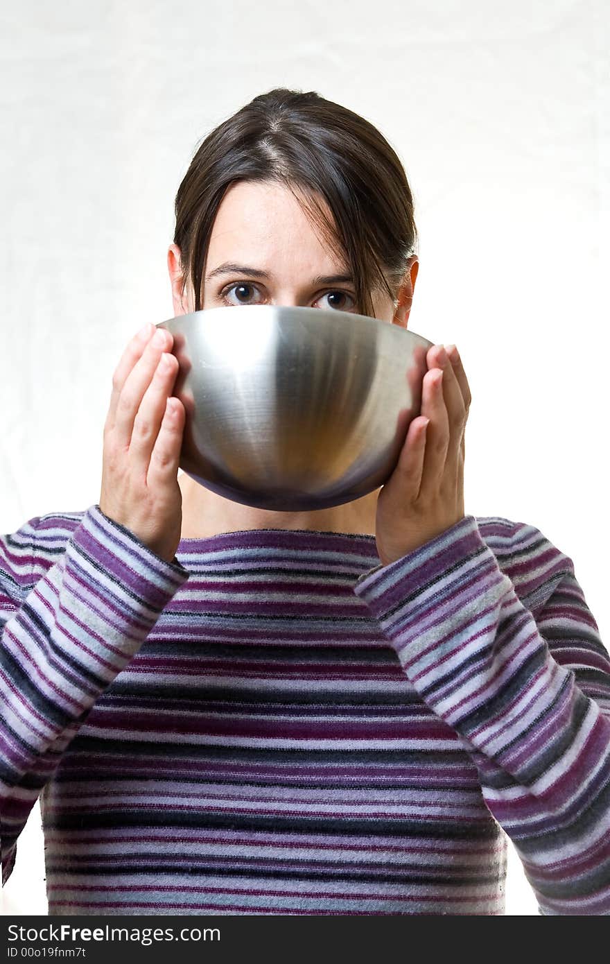 A woman with a white background drinking from a bowl. A woman with a white background drinking from a bowl