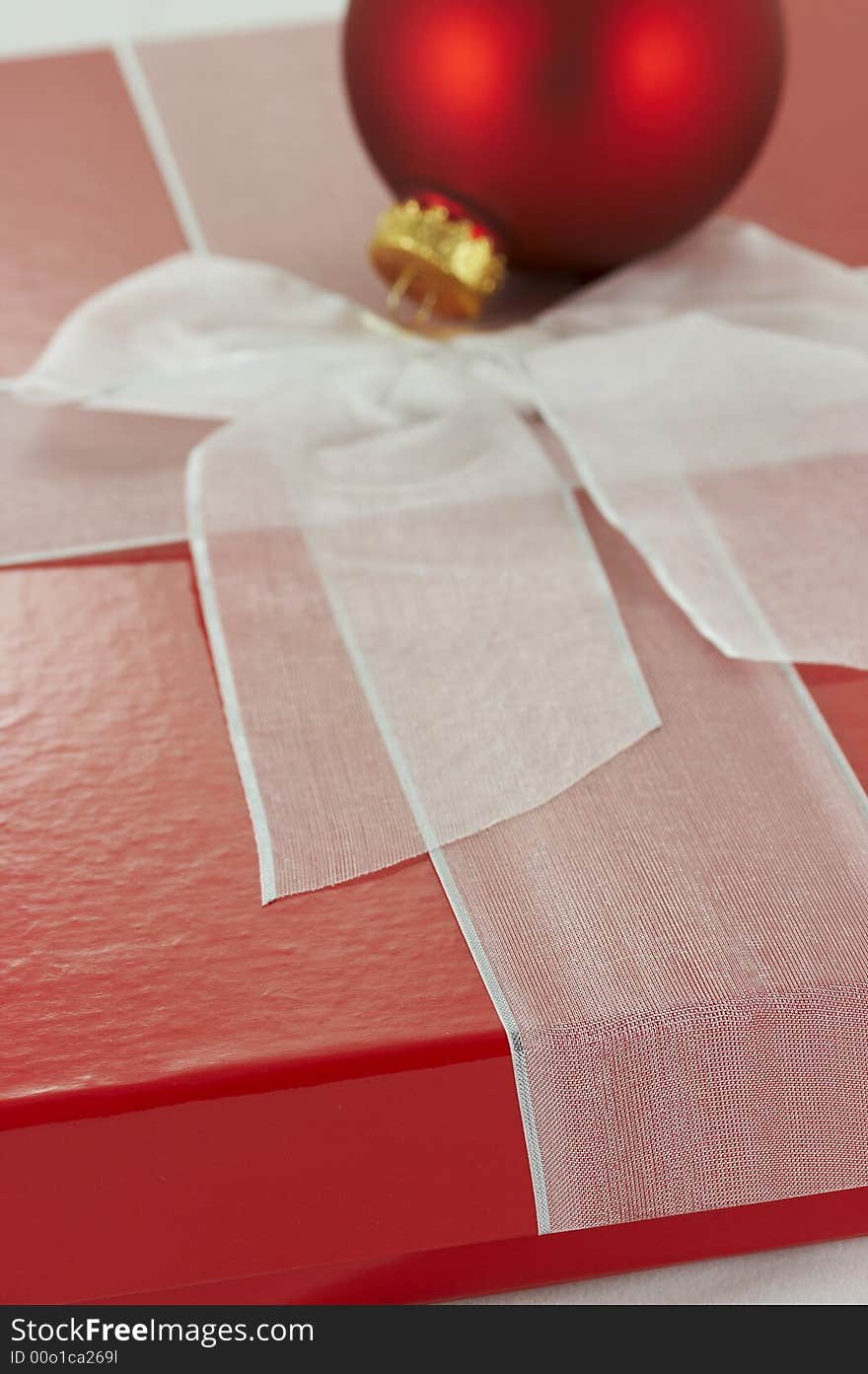 A red box and white ribbon holiday present. A red box and white ribbon holiday present