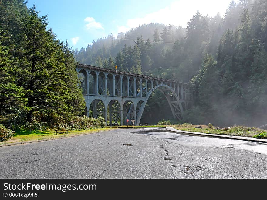 Old railroad bridge over modern paved road as the mist and fog burns off. Old railroad bridge over modern paved road as the mist and fog burns off