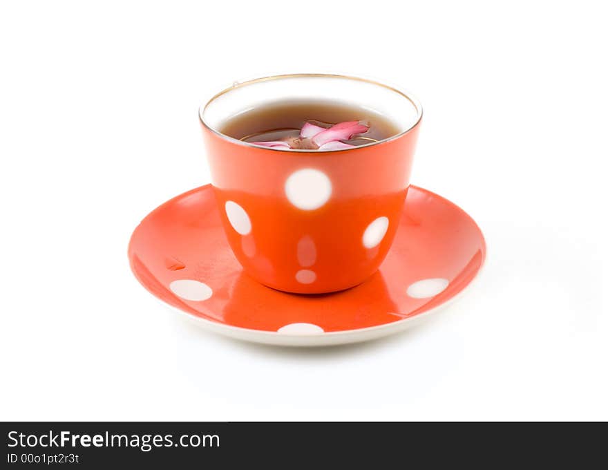 A red punctated saucer and cup with tea adorned with flower isolated on white. A red punctated saucer and cup with tea adorned with flower isolated on white