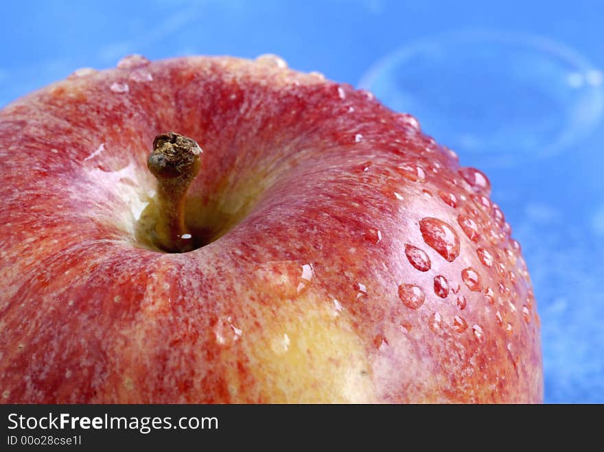 Water drops on apple against blue background