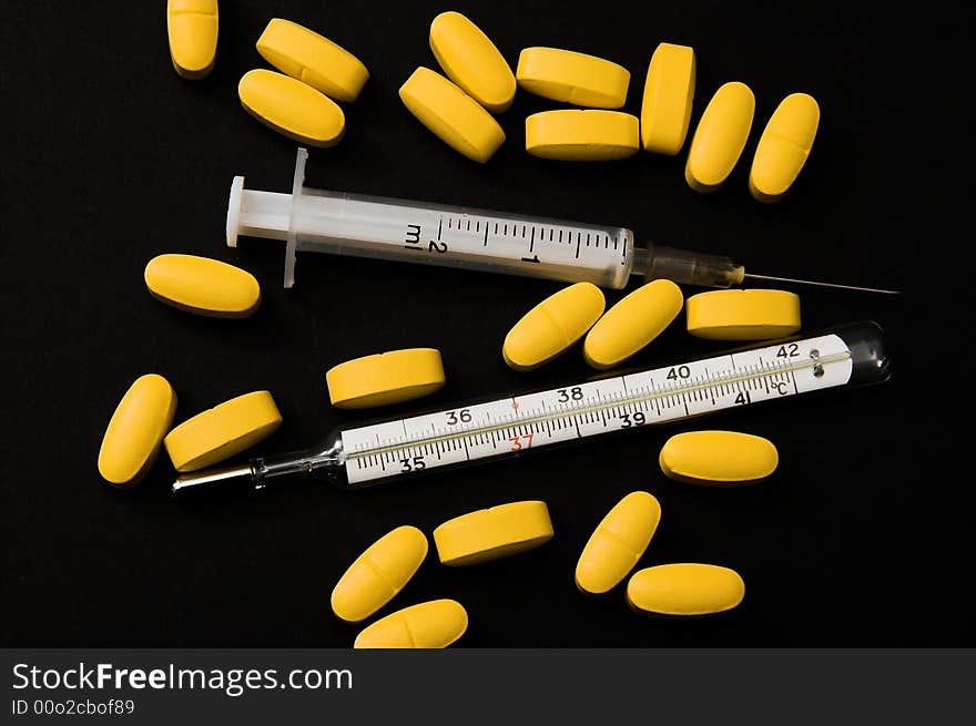 Yellow pills, syringe and thermometer