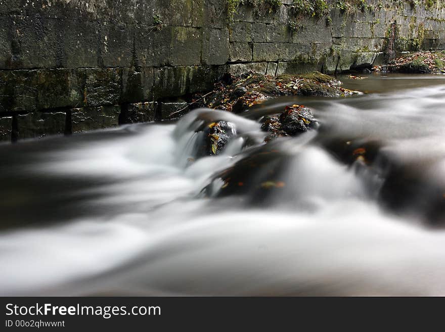 Scenic view of rocky waterfall on Irati river with slow motion blur effect; old wall in background. Scenic view of rocky waterfall on Irati river with slow motion blur effect; old wall in background.